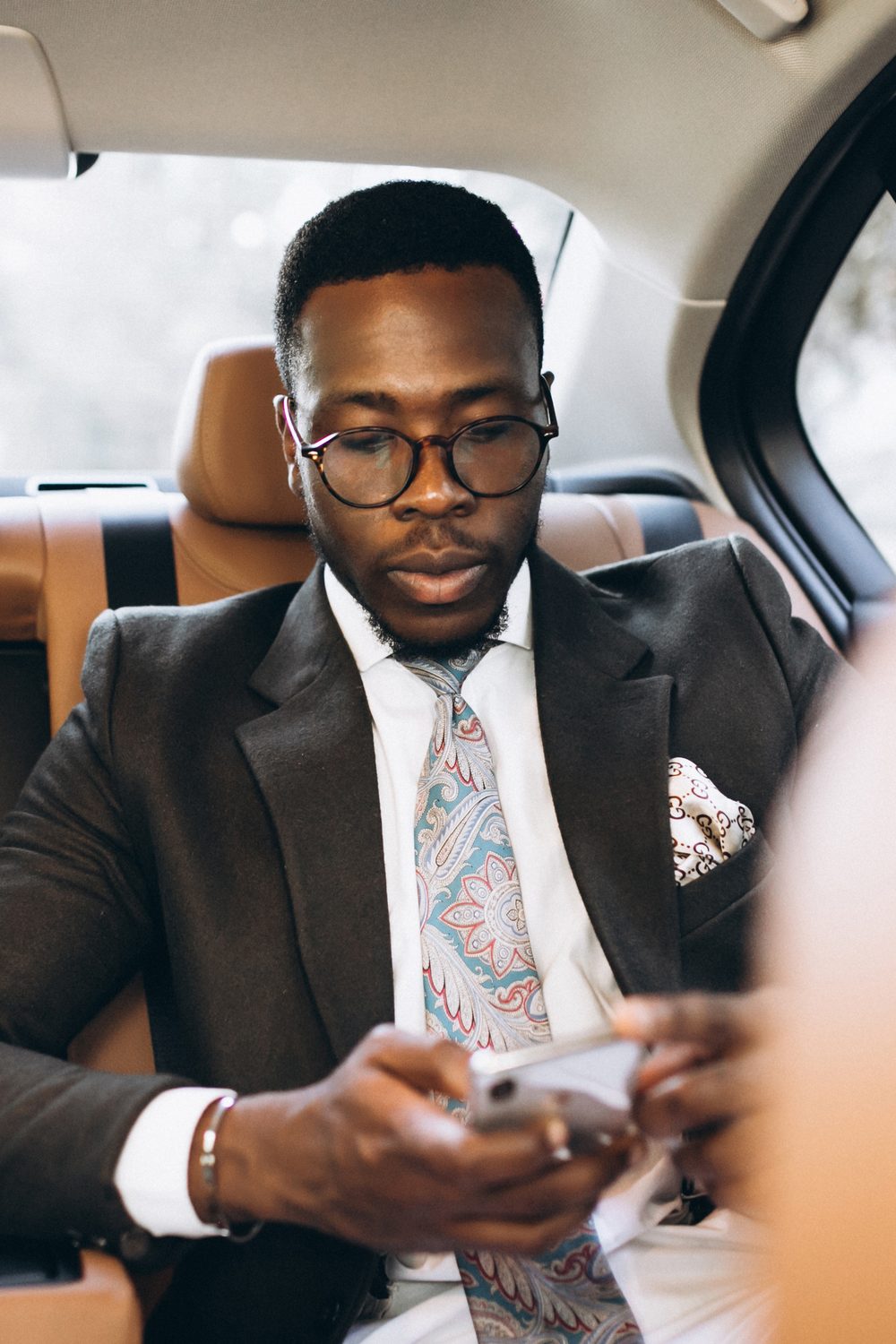 Businessman checking his phone in the back seat of a car