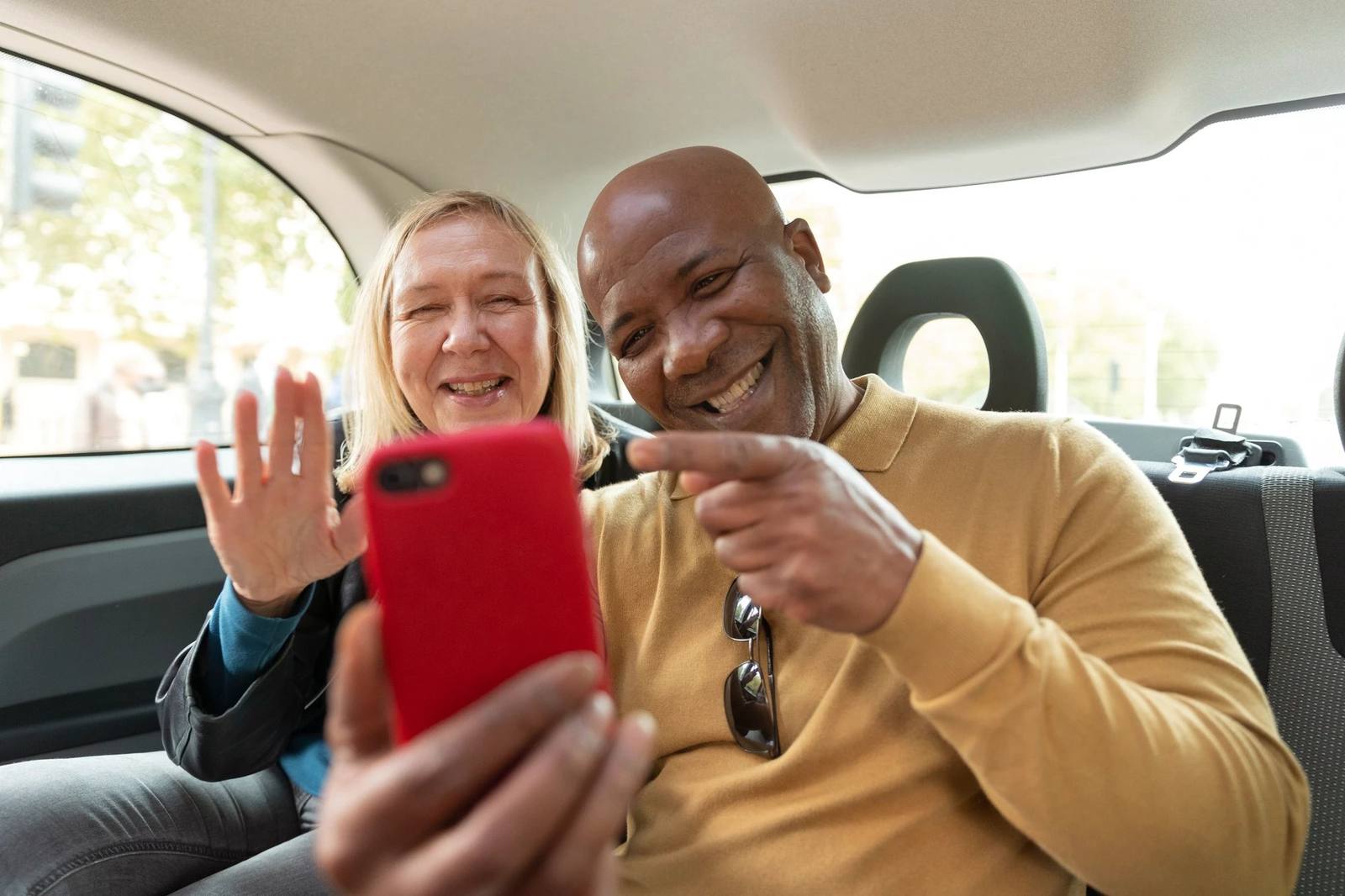 Two passengers smiling at a phone in the back seat of a taxi