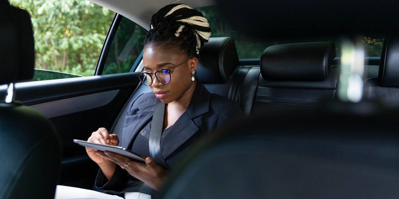 Passenger checking her trip on a tablet in the back seat