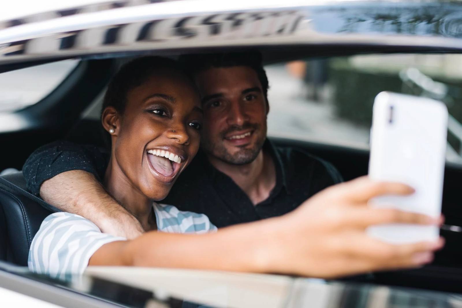 Two passengers taking a selfie through the window of a car
