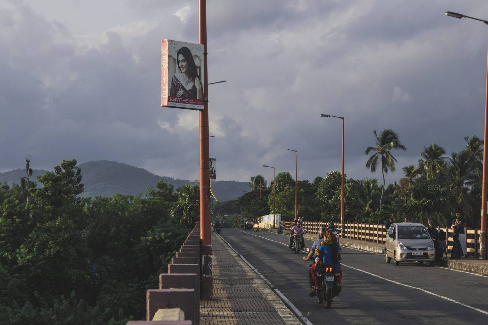Coastal road lined with palm trees and hills